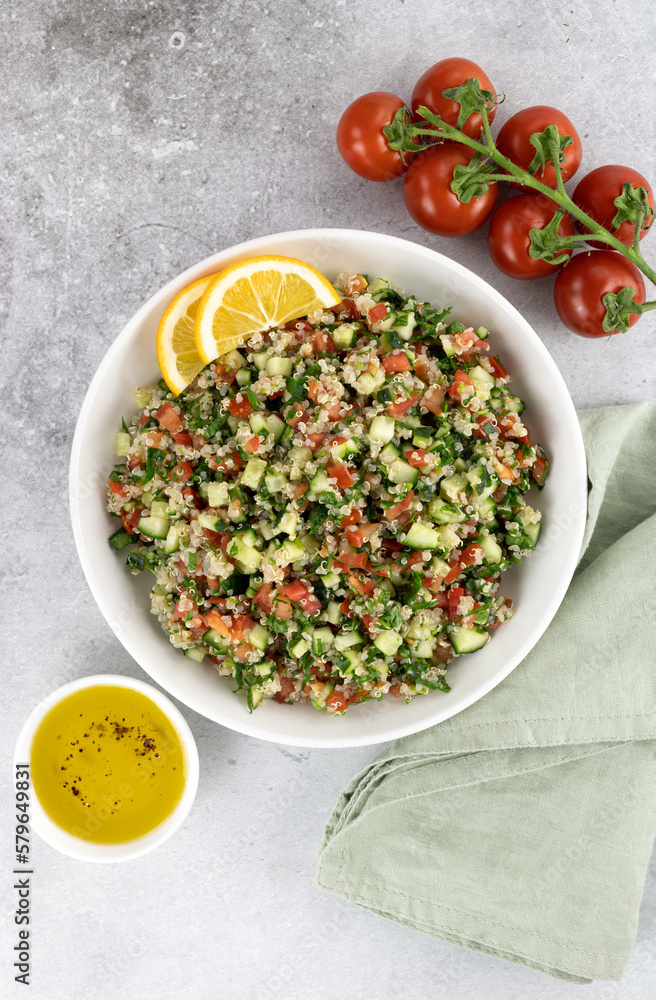 Vegan salad with quinoa, cucumbers, tomatoes, parsley on a gray background. Tabouleh salad. Top view. Vegan salad with quinoa, cucumbers, tomatoes, parsley on a gray background. Tabouleh salad. Top view.