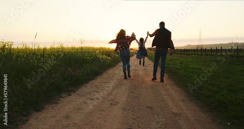 Farm family, walking with child and holding hands on sustainable organic farming healthy plant crop harvest for sustainability. Agriculture farmer, girl kid playing and mom on fun sunset nature walk