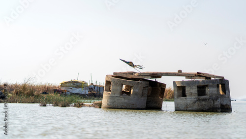 Mesopotamian Marshes in Iraq. Bunkers built by Saddam to enforce clearing of the restive region from Marsh Arabs, with a local dwelling in the background. photo