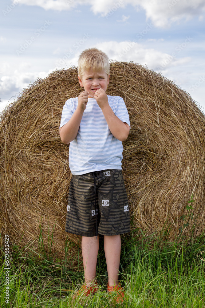A little boy is in a meadow with hay rolls and enjoying the warm summer weather and sun. It's summer break. A little boy is in a meadow with hay rolls and enjoying the warm summer weather and sun. It's summer break.