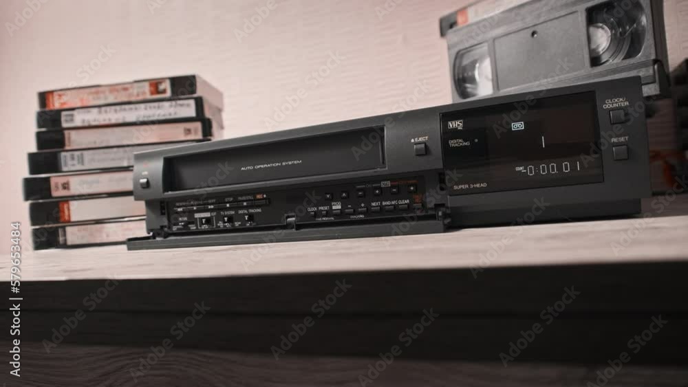 Male hand pulls out VHS from a vintage videotape recorder. Eject VHS