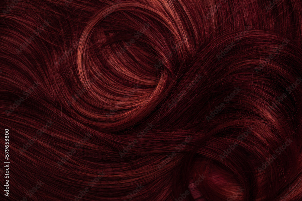 Naklejka premium Dark red hair close-up as a background. Women's long brown hair. Beautifully styled wavy shiny curls. Coloring hair with bright shades. Hairdressing procedures, extension.