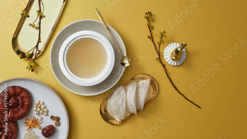 A white bowl containing bird’s nest soup arranged with edible bird’s nest and a dish of many types of herb. Bird's nest is rare medicine and has a very high nutritional value