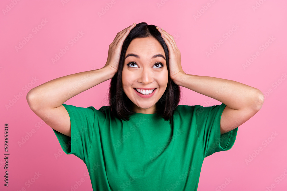 Portrait of astonished cheerful girl arms touch head look up empty space isolated on pink color background Portrait of astonished cheerful girl arms touch head look up empty space isolated on pink color background