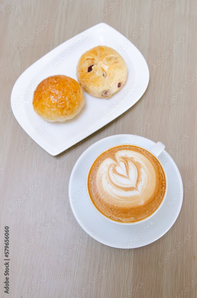 A wooden table with a fragrant cappuccino and baked bread A wooden table with a fragrant cappuccino and baked bread