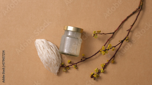 Bird’s nest raw and glass bottle without label, yellow flower branch on brown background. Mockup scene for product. Bird's nest is an expensive culinary ingredient for health.