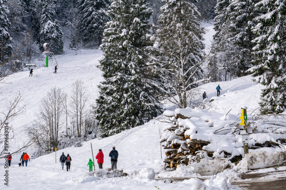 Menschen spazieren durch eine verschneite Winterlandschaft in den bayerischen Alpen