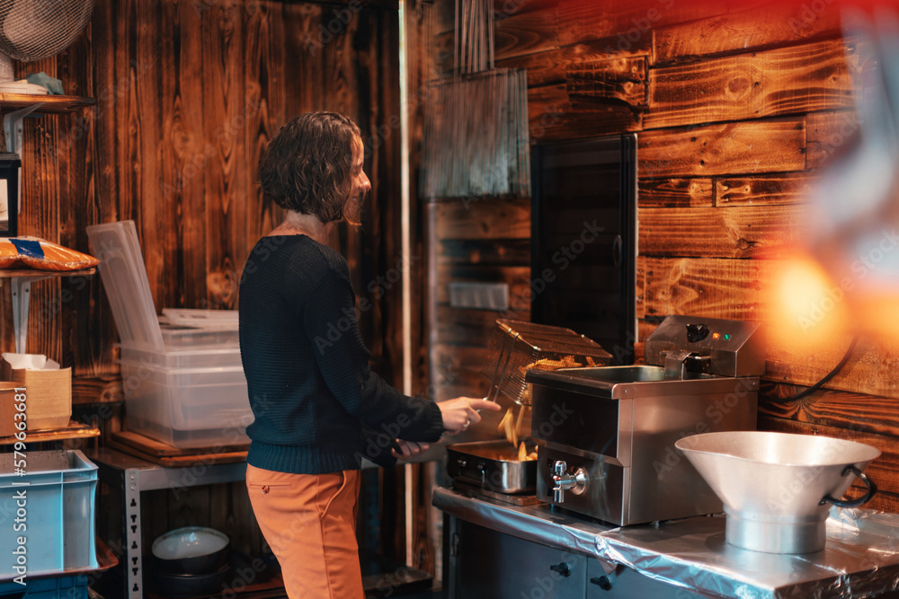 woman in a typical Belgian kiosk preparing french fries in the fast ...