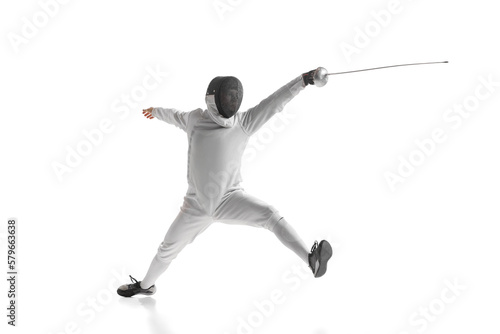 Professional male fencer in fencing costume training with sword isolated on white studio background. Concept of sport, competition, professional skills, achievements