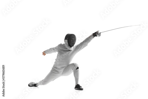 Dynamic portrait of male athlete in fencing costume with sword in hand in action isolated on white studio background.