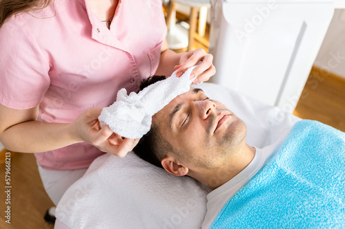 Beautician doing face treatment in beauty salon to a man.