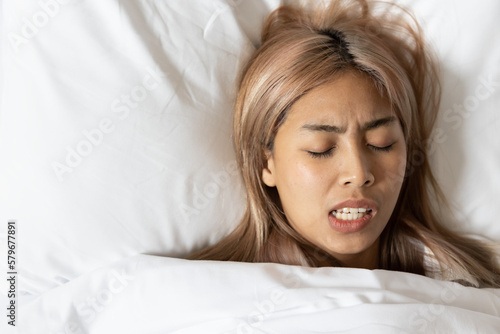 Fototapeta Tired and stressed Asian woman with colored hair sleeping, having bad dream, nig