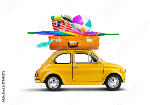 Retro yellow car with luggage and beach equipment on the roof. Summertime vacation road trip concept.