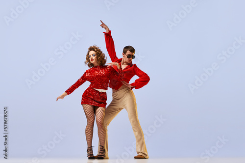 Tableau sur toile Young beautiful couple of dancers in bright retro fashion clothes, stage costumes dancing over lilac color background