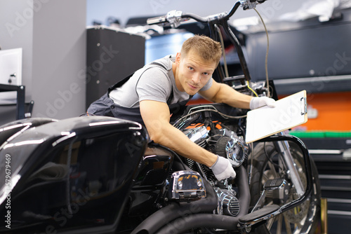 Male mechanic diagnoses modern motorcycle in service center