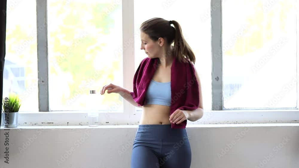 Young woman taking a break from workout and drinking water Young woman taking a break from workout and drinking water