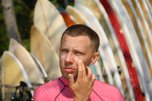 Photography Man surfer applies protective zinc on his face