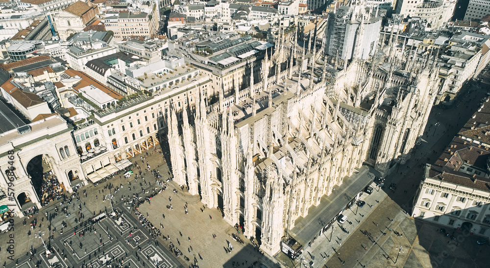 Aerial view of Piazza Duomo in front of the gothic cathedral in the center. Drone view of the gallery and rooftops during the day. Milan, Italy. High quality photo