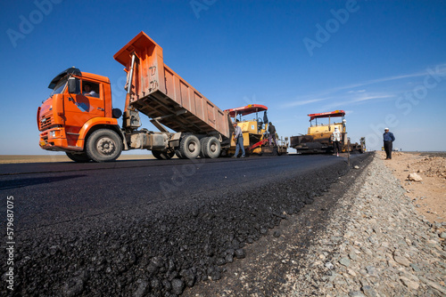 Kyzylorda province, Kazakhstan, April 29, 2012: Dump truck unloads hot asphalt. Construction of West Europe-West China new highway