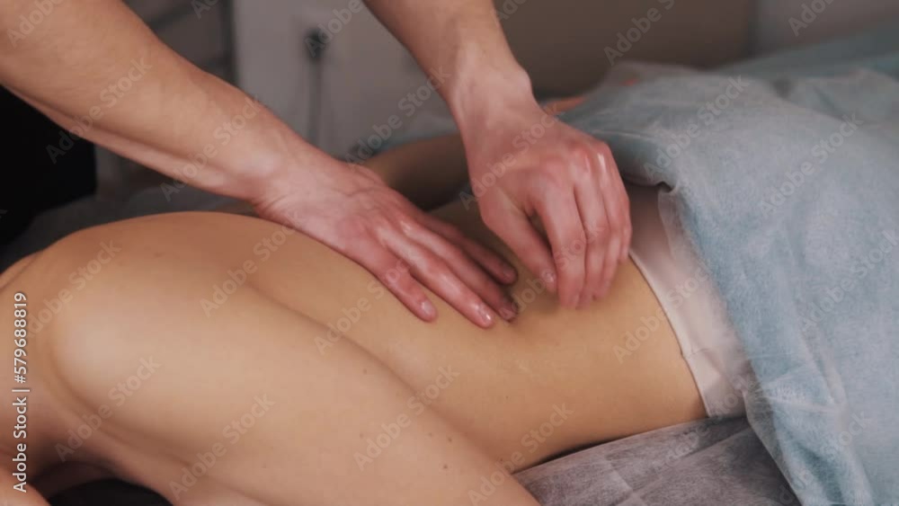 A close-up of a gentle massage by a man's hands on the back of a young woman A close-up of a gentle massage by a man's hands on the back of a young woman
