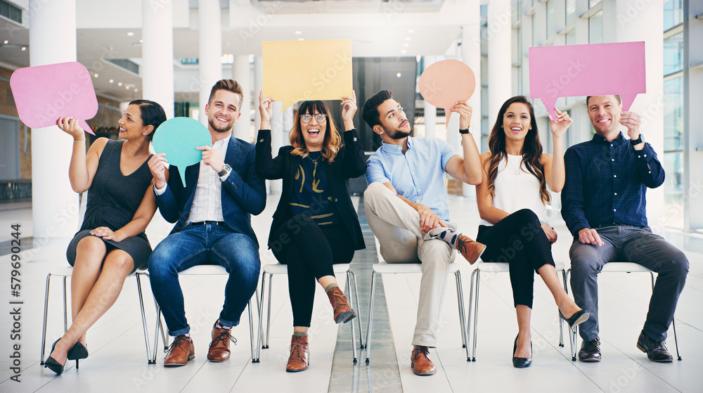 Naklejka premium Im the ideal candidate because...Shot of a group of businesspeople holding colorful speech bubbles while waiting in line in a modern office.