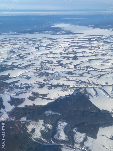 View from the plane window to the snow-covered expanses with ravines.
