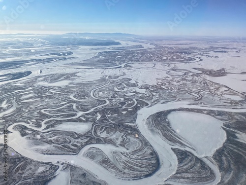 Abstract winter panorama with snow-covered territory - forests, fields and winding rivers.