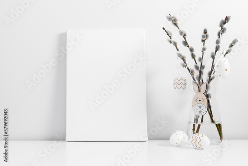 Easter holiday composition. White linen blank canvas mockup, vase with willow plant branches, easter eggs, bunny on white table. Front view.