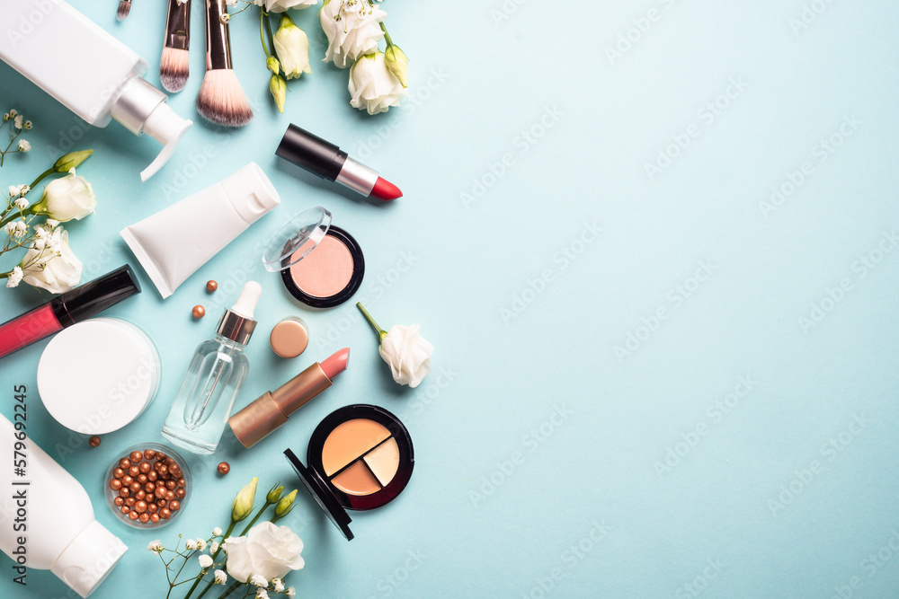 Make up professional cosmetics on blue background. Cream, powder, shadow, brushes with green leaves and flowers. Flat lay image with copy space. Make up professional cosmetics on blue background. Cream, powder, shadow, brushes with green leaves and flowers. Flat lay image with copy space.