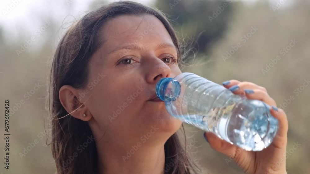 Woman drinking water in public park after sport training, hiking on holidays. Rehydration after sport training, importance of drinking water to avoid dehydrate. Woman drinking water in public park after sport training, hiking on holidays. Rehydration after sport training, importance of drinking water to avoid dehydrate.