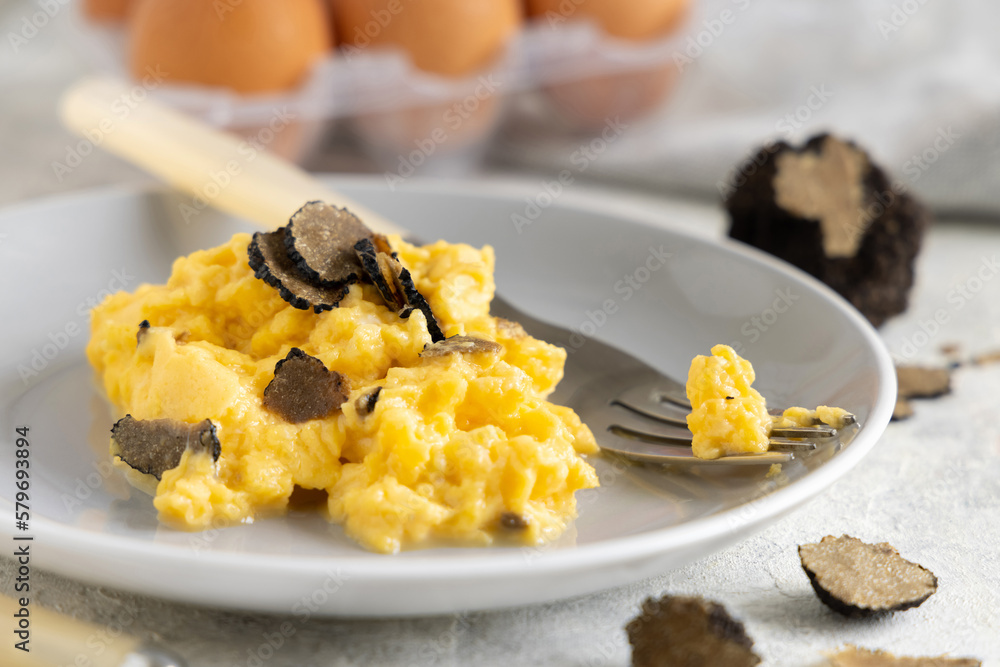 Scrambled eggs with fresh black truffles from Italy served in a plate close up, gourmet breakfast Scrambled eggs with fresh black truffles from Italy served in a plate close up, gourmet breakfast