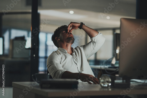 I just cant focus. Shot of a young businessman looking stressed out while working on a computer in an office at night.