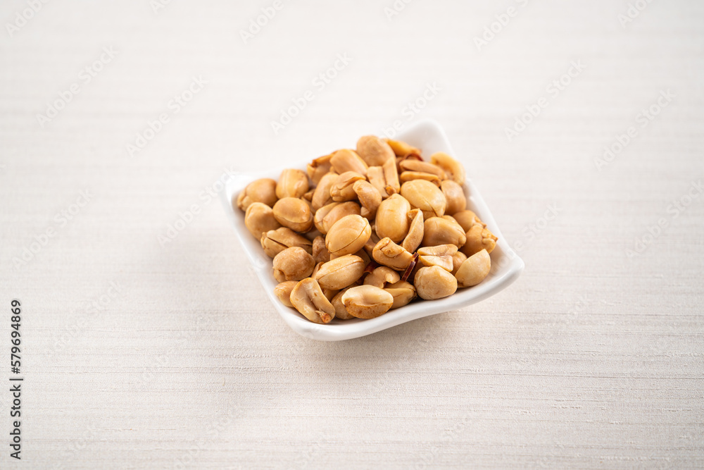 Spicy flavored peanut kernel in a bowl on white table background. Spicy flavored peanut kernel in a bowl on white table background.
