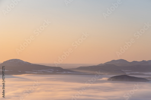 霞んだ夜明けの山々のシルエットと靄に覆われた湖。 © Masa Tsuchiya