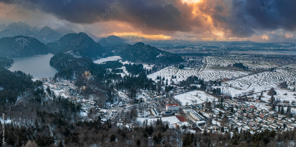 Aerial view of the Neuschwanstein Castle or Schloss Neuschwanstein on a winter day, with the mountains and trees capped with snow all around it.