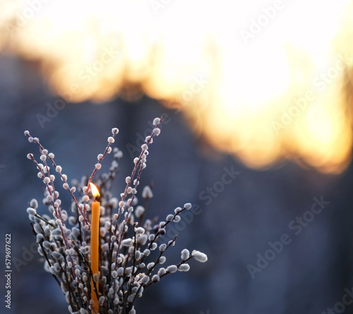 Valokuva Burning candle and willow branches on abstract blurred natural dark background