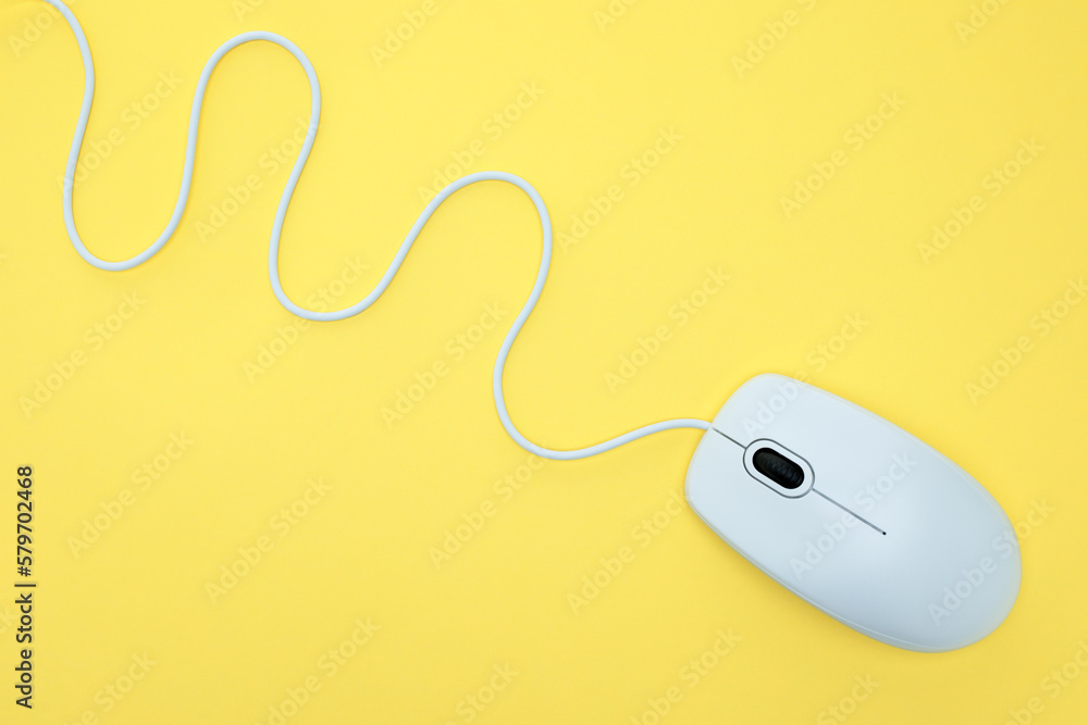 White modern wired computer mouse on yellow background White modern wired computer mouse on yellow background