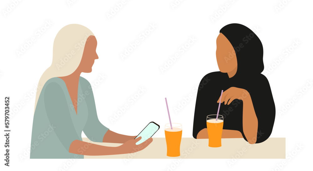 Portrait of two young women talking at table. The concept of friendship or business between people of different cultures. Portrait of two young women talking at table. The concept of friendship or business between people of different cultures.