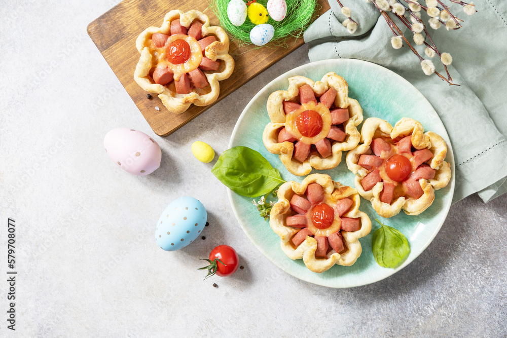 Idea for Easter breakfast or lunch. Mini pizza. Pizza in puff pastry with cheese and tomatoes on the festive table. View from above. Copy space. Idea for Easter breakfast or lunch. Mini pizza. Pizza in puff pastry with cheese and tomatoes on the festive table. View from above. Copy space.