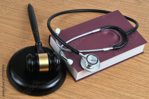 Concept d'erreur médicale avec un stéthoscope posé sur un livre et un marteau de juge sur un fond en bois