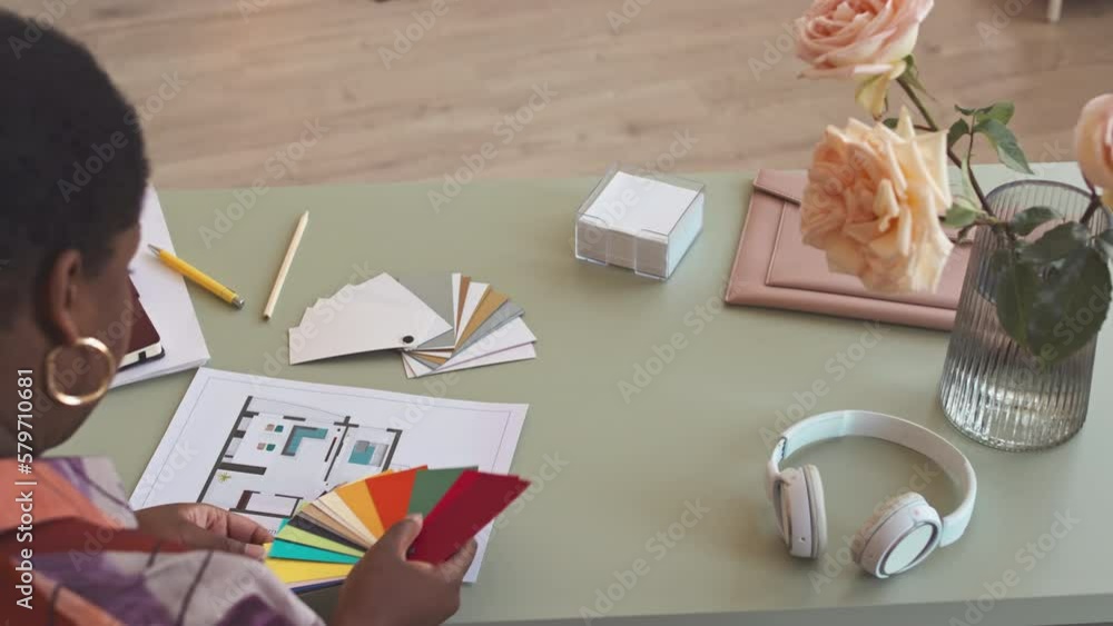 From above shot of African American female interior designer looking at ...