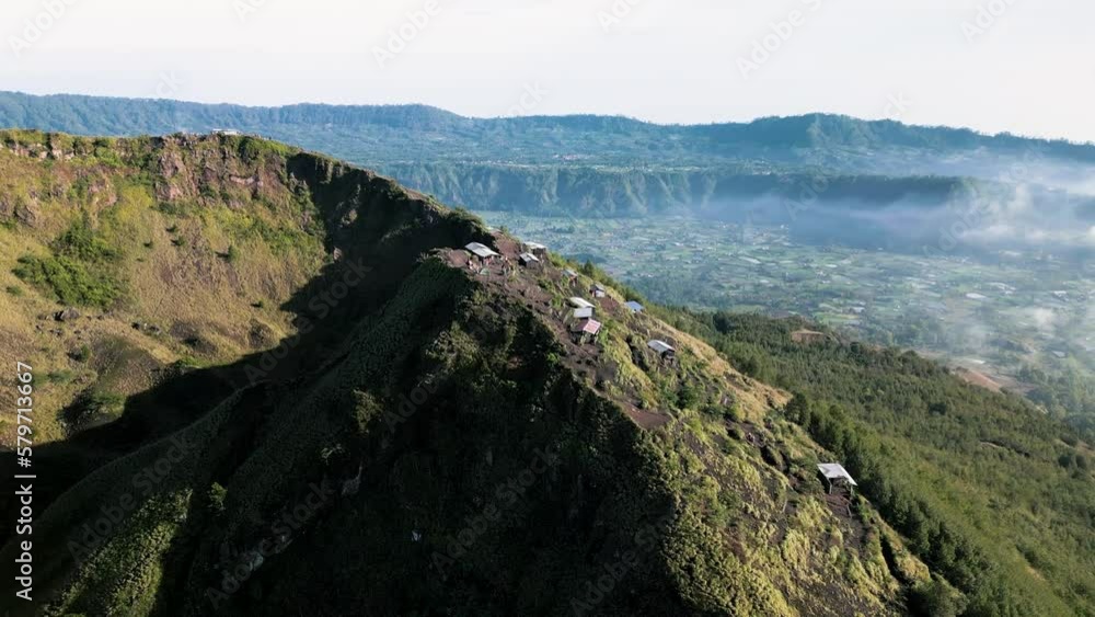Sunrise at the top of Batur volcano. People walk along the caldera. Shooting from a drone. Bali, Indonesia Sunrise at the top of Batur volcano. People walk along the caldera. Shooting from a drone. Bali, Indonesia