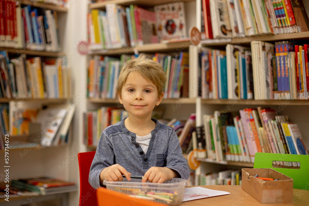 Adorable little boy, sitting in library, reading book and choosing what to lend, kid in book store. Adorable little boy, sitting in library, reading book and choosing what to lend, kid in book store.