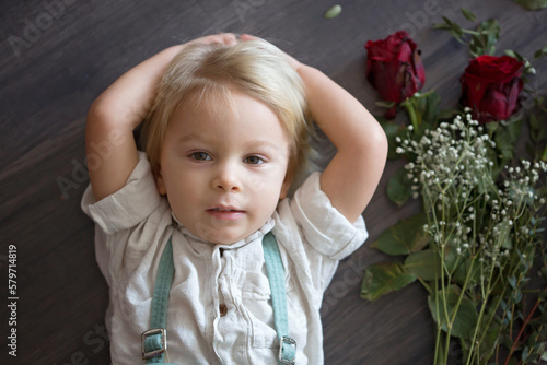 Beautiful toddler boy, holding red roses for mother's day