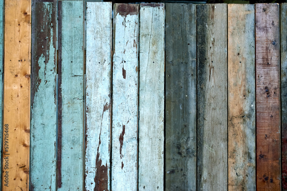Old shabby wooden wall with tiles of various colors. 
