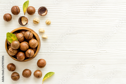 Wooden bowl of shelled macadamia nuts with leaves
