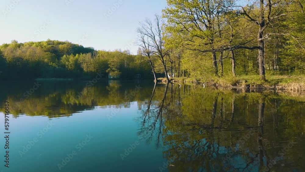Trees and an old yellow house are reflected in the pond. Warm day in early spring Trees and an old yellow house are reflected in the pond. Warm day in early spring