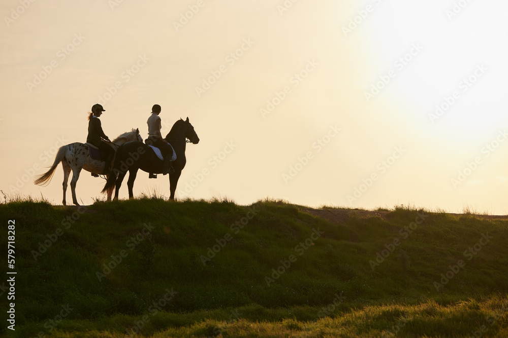 A horse is the projection of peoples dreams. Shot of two unrecognizable women riding their horses outside on a field.