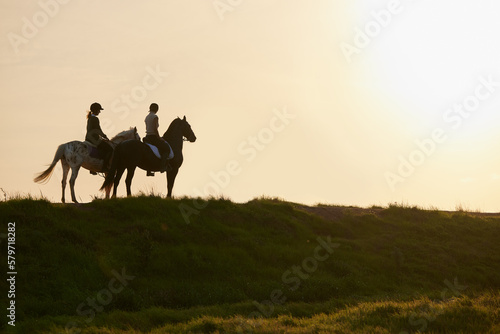 A horse is the projection of peoples dreams. Shot of two unrecognizable women riding their horses outside on a field.