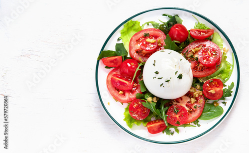 Delicious caprese salad with tomatoes and mozzarella cheese with fresh leaves. Italian food.